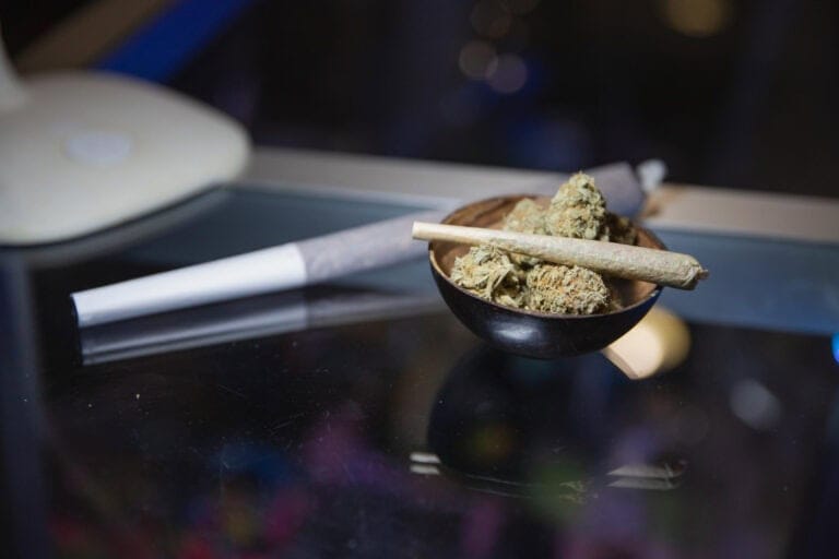 Cannabisblommor och en rullad joint i en skål av trä