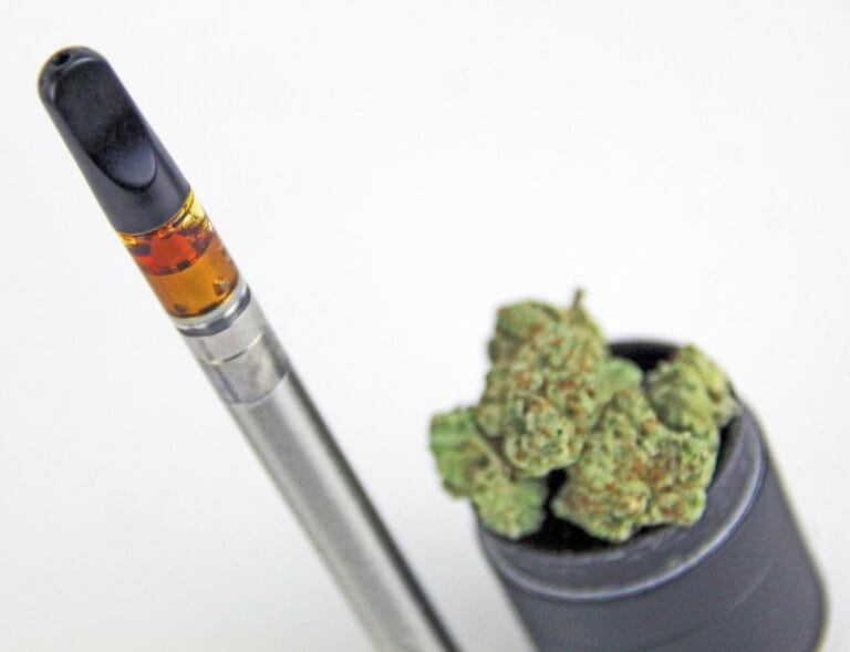 CBD-vapepatron bredvid CBD-blommor i en grinder